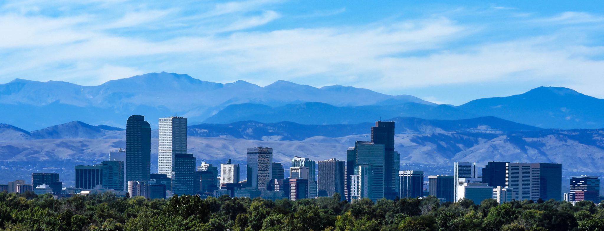 The skyline of Denver, Colorado with the foothills and Rocky Mountains in the distance.